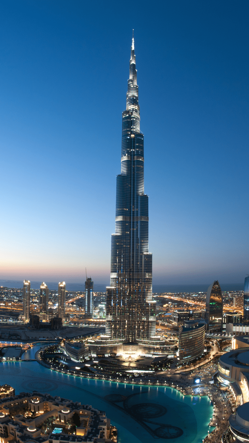 Burj Khalifa towering over Dubai skyline at dusk, with illuminated skyscrapers and a winding waterfront below